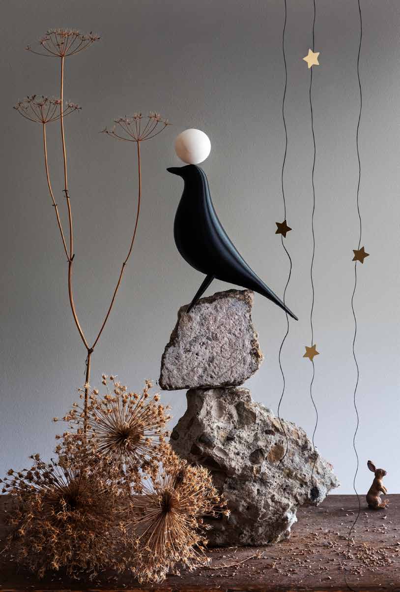 The Moon Was as Full as the Night Was Still A large black bird sits atop a stack of rocks. To the left of the rocks are small plant sprigs. To the right of the rocks are stars hanging from the top and a small rabbit on the ground. On top of the birds head is a small white sphere depicting the moon.