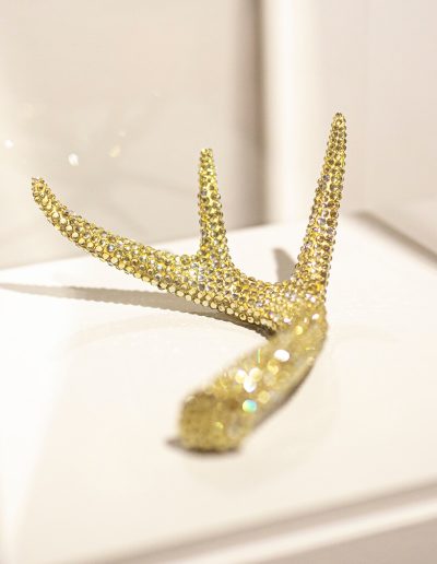 An animal's antler bedazzled with golden beads.