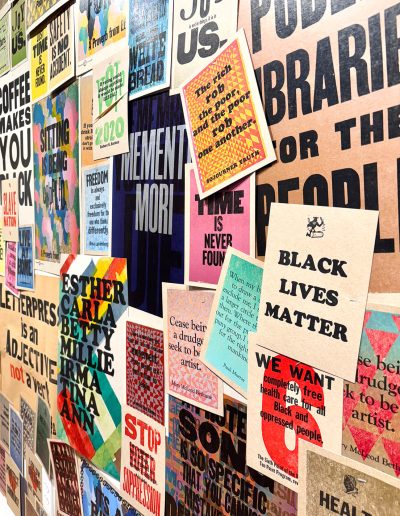 A close-up photograph of a wall of posters, each poster depicting a message