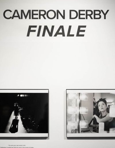 A row of black and white photographs documenting a ballet recital performance. The writing on the wall above the photos says "Cameron Derby: Finale" which is the artist and title of the show.