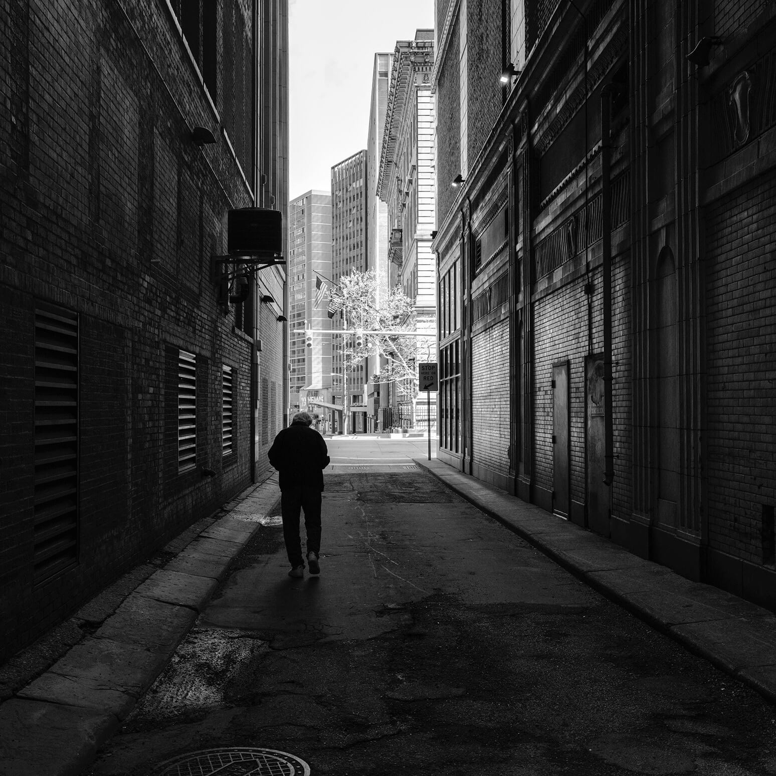 black and white photo of city alley with man walking