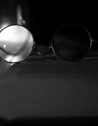 Black and white photo of glasses laying on a book in a dark room