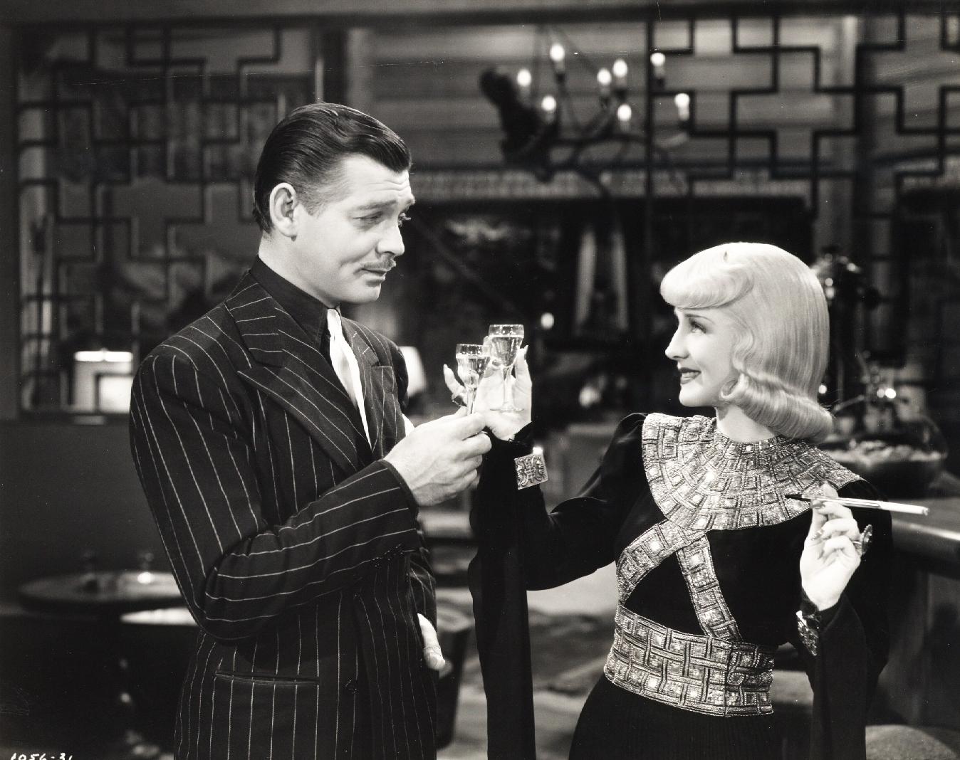Hollywood-Stills Black and white old style photo of a man and woman clinking champagne glasses. The man is wearing a black suit with white pinstripes and the woman is wearing a formal dress