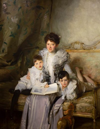 a formal portrait of Mrs. Knowles and her 2 children sitting on a bench reading a book. Each family member has dark hair with brown eyes.
