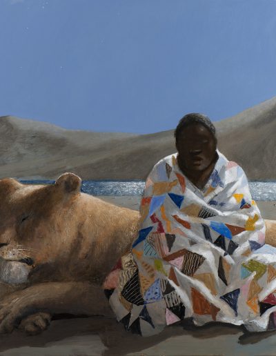 A black man sitting on sandy ground, a colorful quilted blanket is draped around him. Behind him is a large female lion with closed eyes.