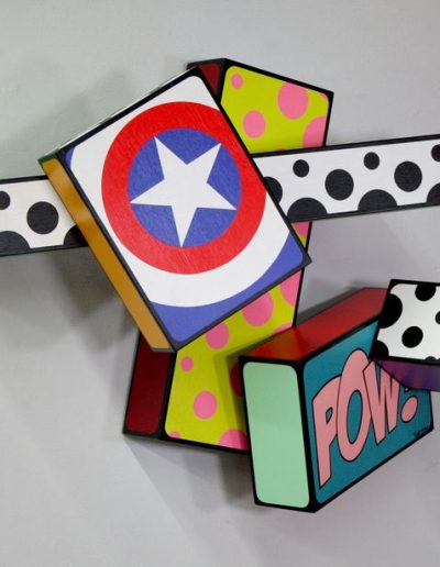 Art structure of 5 different size blocks with colorful patterns. One has the Captain America log, one says POW!, the others have polka dots.