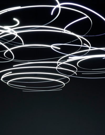 Closer Image of lights that are spinning and seem to leave a trail of glowing light as they spin. The background is very dark, making the lights look as though they are hovering.